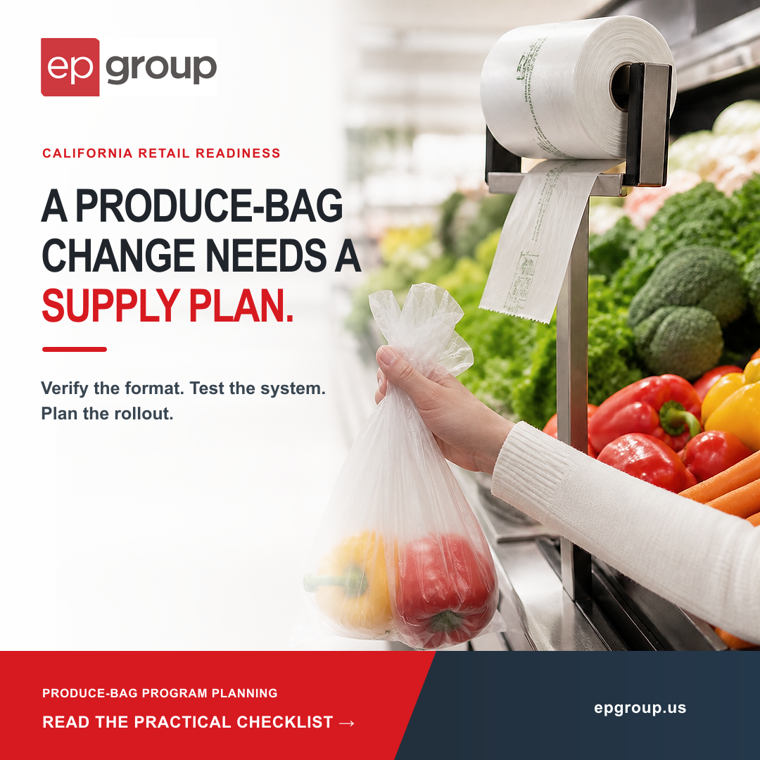 A shopper holds a produce bag beside a roll dispenser and fresh vegetables in a grocery produce department.