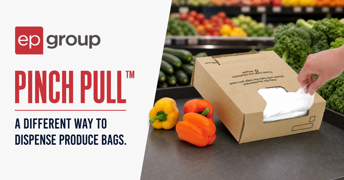 A shopper pulls one clear produce bag from an authentic Pinch Pull cardboard dispenser beside three peppers in a grocery produce department.